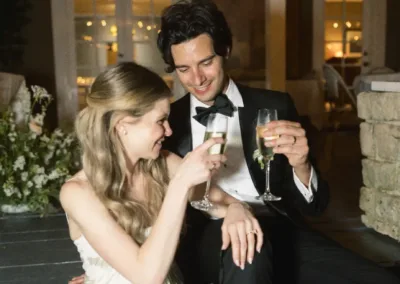 Couple in formal wear with champagne glasses sitting on steps at night.