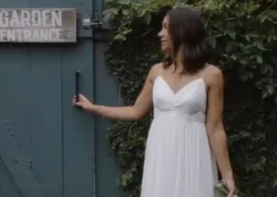 Woman in white dress opening a garden gate.